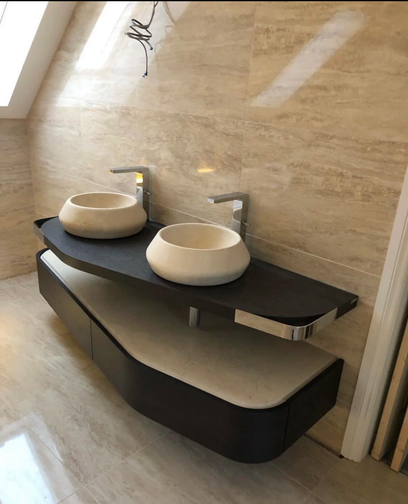 Twin stone vessel basins on a curved floating vanity with travertine tiling — luxury bathroom installation Woking