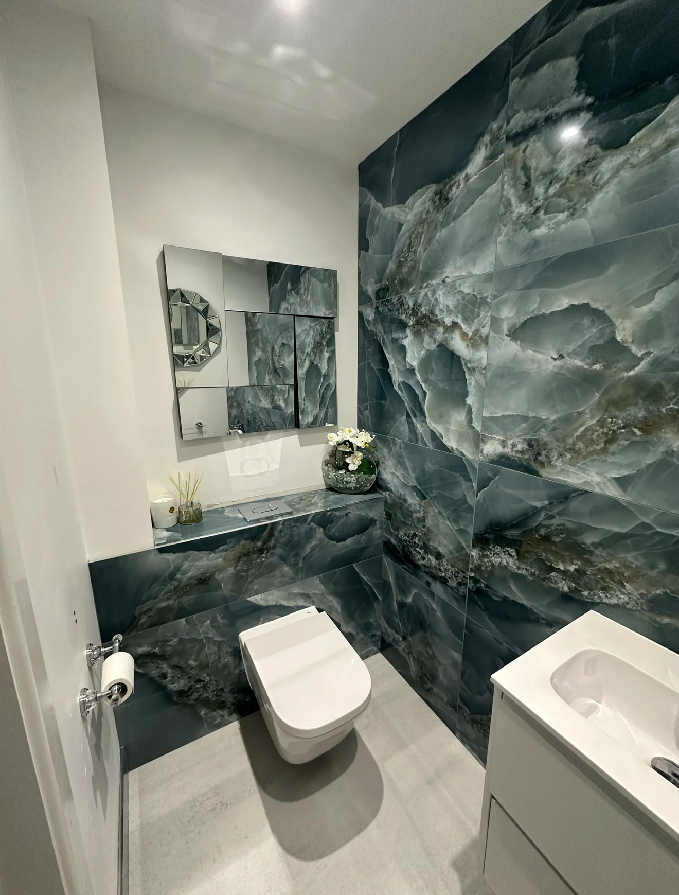 Cloakroom with dramatic blue onyx feature wall and wall-hung WC — bathroom design Woking