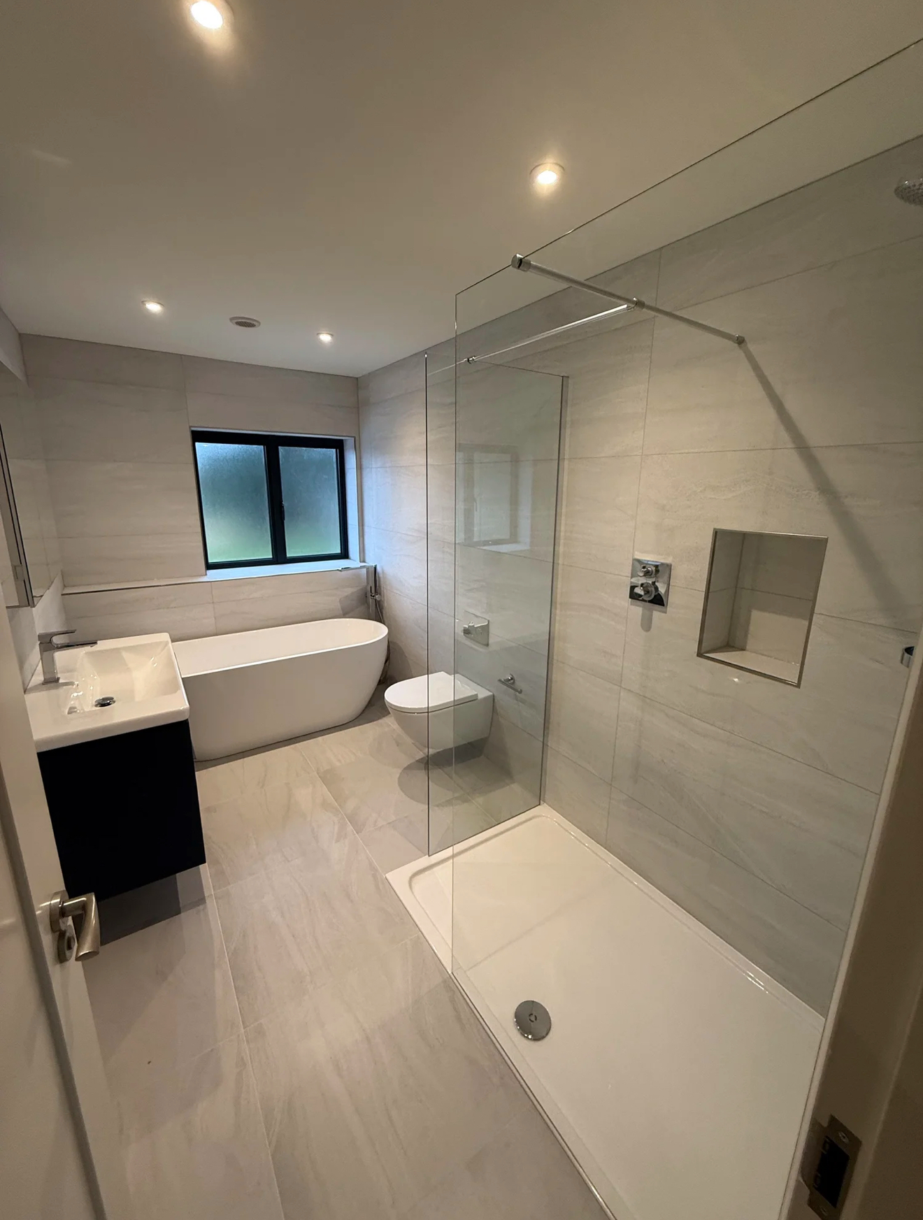 Modern family bathroom with freestanding bath, walk-in shower and navy vanity unit — bathroom renovation Woking